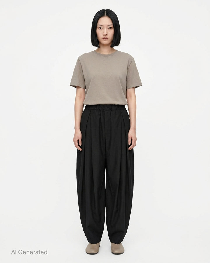 Comme des Garçons Black pleated balloon trousers in a herringbone wool blend with an elasticated waist, shown from the front - front