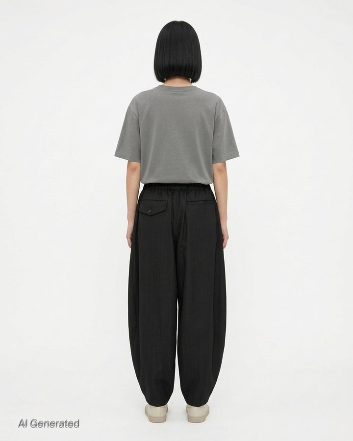 Comme des Garçons Black pleated balloon trousers in a herringbone wool blend with an elasticated waist, shown from the front - back