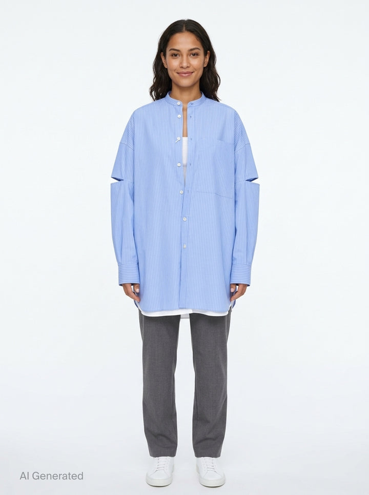 Enfold pale blue pinstripe oversized shirt with deconstructed cut-out sleeves, mandarin collar, white button placket, and a contrast white underlayer at the hem - front