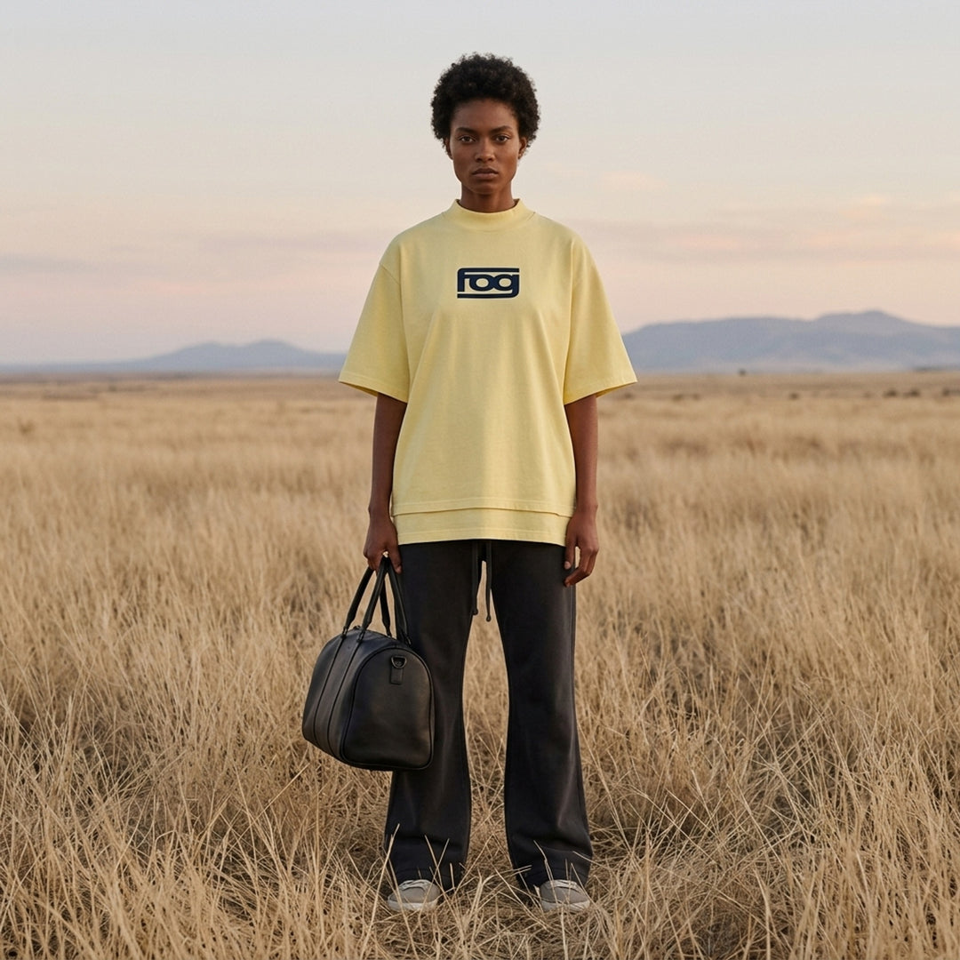 Fear of God ESSENTIALS Panelled Modern Tee in deep teal with a yellow logo graphic at the chest, shown from the front - lifestyle