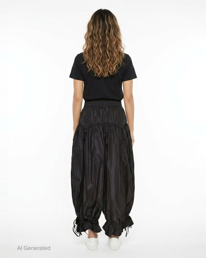 Ganni Flyweight Nylon Balloon Pants in black, featuring a smocked yoke, voluminous gathered body, and ruched tie ankles, displayed flat on a white background - back