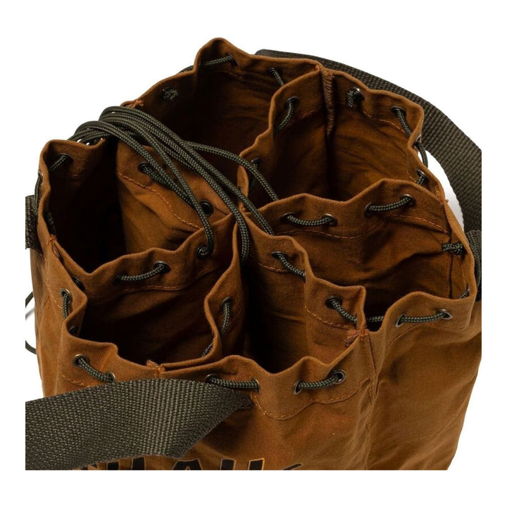 Human Made Drawstring Bucket Bag in tan waxed canvas with olive webbing handles, golden heart logo patch, and bold typographic branding on the exterior - packshot