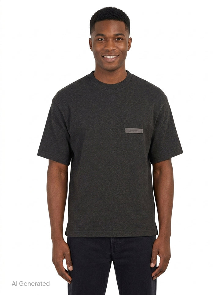 Jacquemus Le T-Shirt Ruban in charcoal grey, featuring a boxy silhouette, crew neckline, and a tonal signature woven label patch at the chest - front
