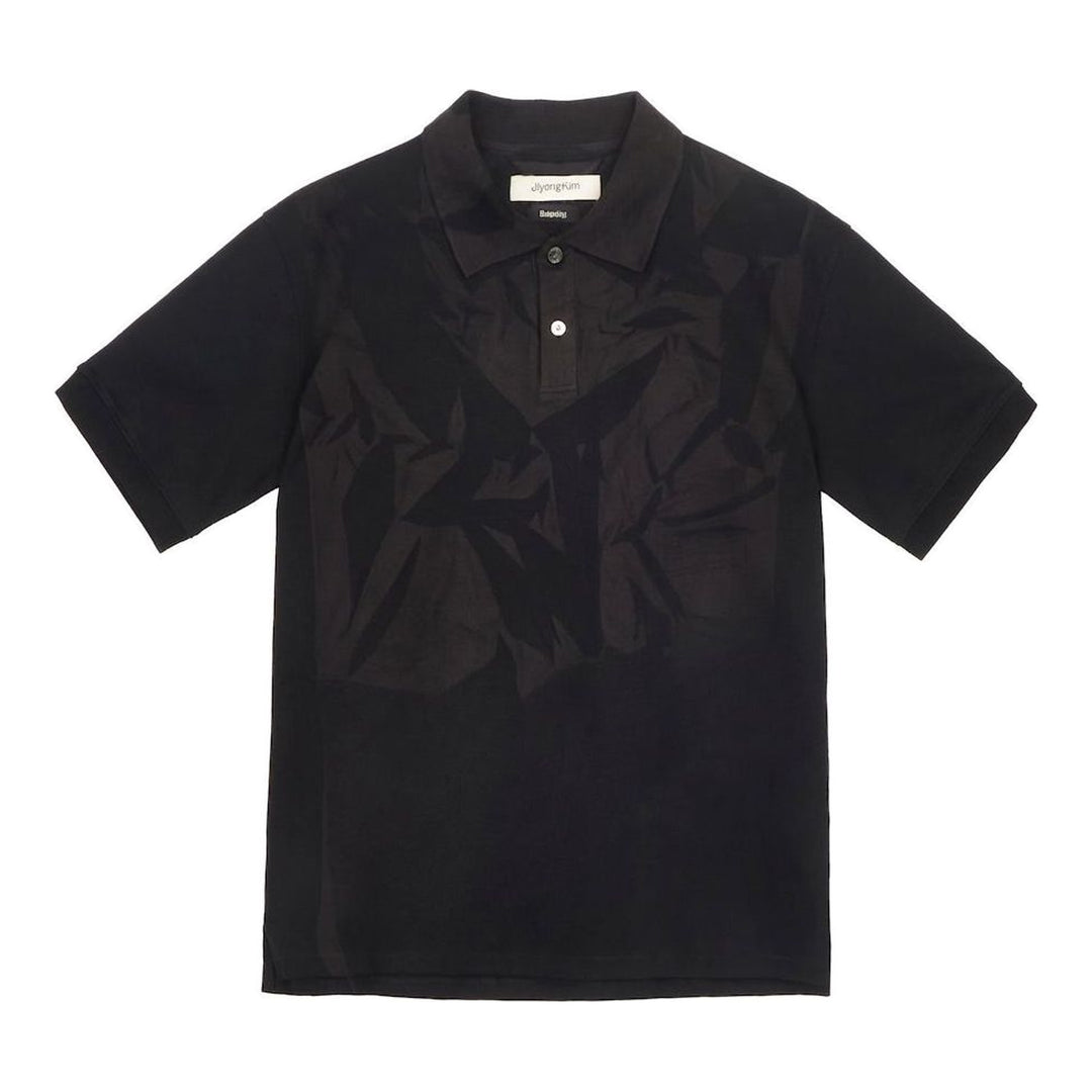 JiyongKim Sun-Bleached Pack Polo in black, displayed flat, featuring a tonal crumpled-fabric graphic panel across the front chest and a two-button placket - packshot
