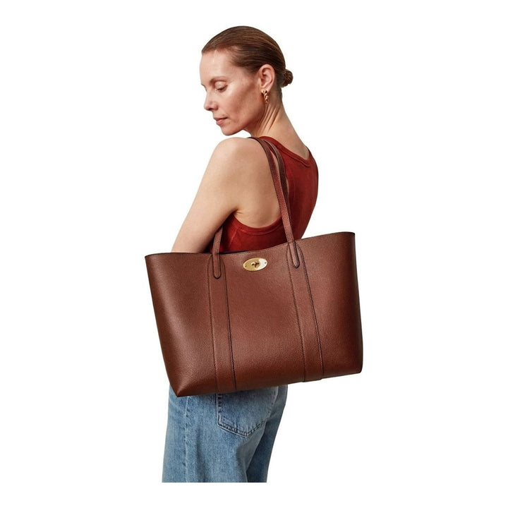 Mulberry Bayswater Two Tone Tote in tan pebbled leather with gold postman's lock closure and navy interior lining, shot against a neutral background - packshot