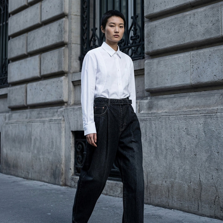 sacai belted wide-leg barrel jeans in washed black denim with deep front pleats, contrast stitching, and tapered hem, photographed flat on white background - lifestyle